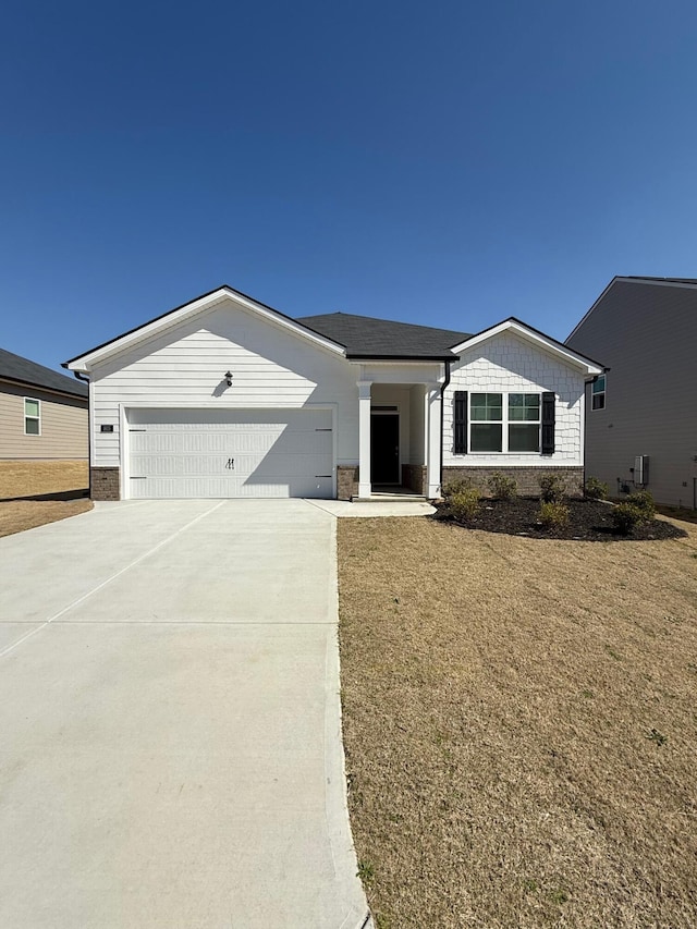 view of front of property featuring stone siding, driveway, and a garage