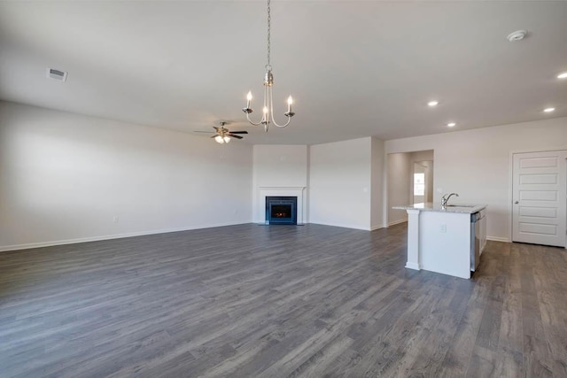 unfurnished living room with dark hardwood / wood-style flooring, ceiling fan with notable chandelier, and sink