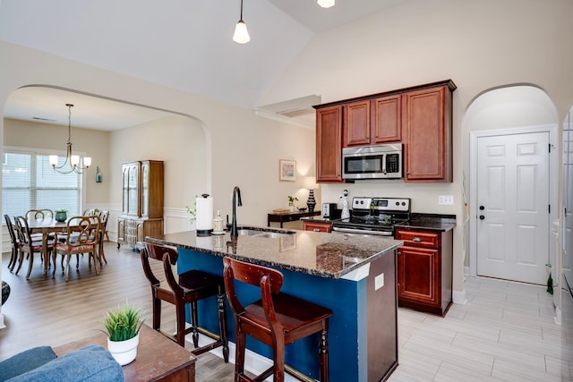 2306 Peach Blossom Pass, Hephzibah, GA 30815 - kitchen featuring stainless steel appliances, arched walkways, a chandelier, dark stone countertops, and wainscoting