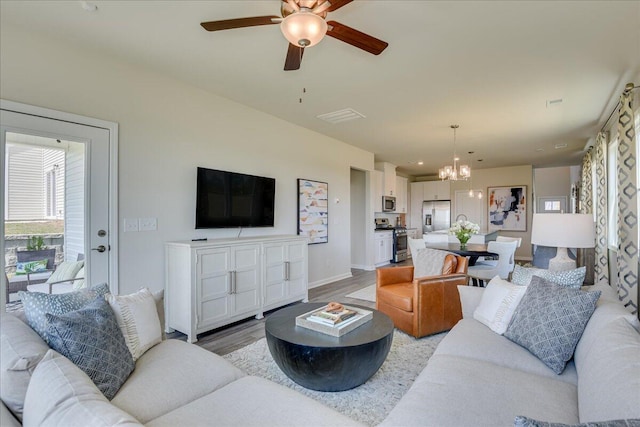 living room with ceiling fan with notable chandelier and hardwood / wood-style flooring