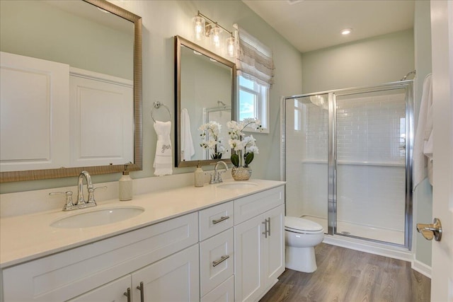 bathroom featuring hardwood / wood-style floors, vanity, toilet, and a shower with door