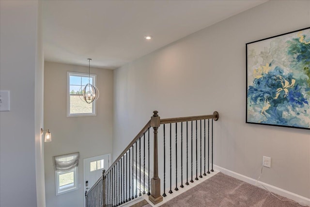 stairs featuring a chandelier and carpet