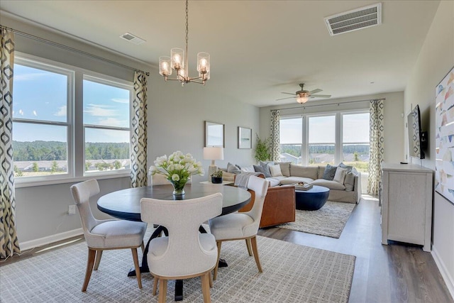 dining space with hardwood / wood-style floors and ceiling fan with notable chandelier