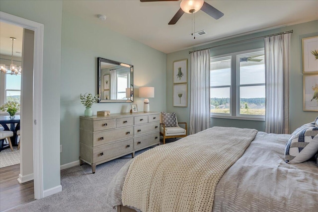 carpeted bedroom with ceiling fan with notable chandelier