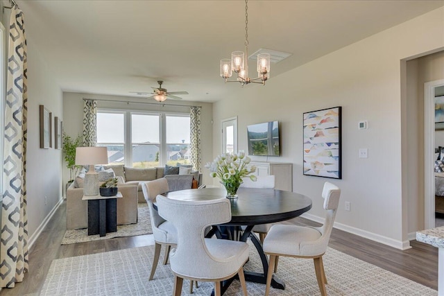 dining room with dark wood-type flooring and ceiling fan with notable chandelier