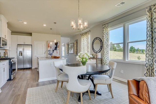 dining room featuring light hardwood / wood-style floors, a notable chandelier, and sink