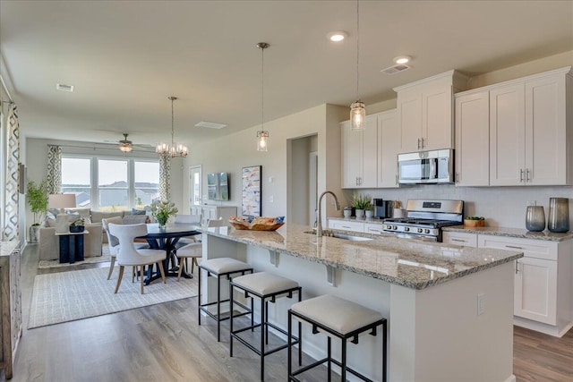 kitchen featuring stainless steel appliances, ceiling fan, a kitchen island with sink, sink, and white cabinets