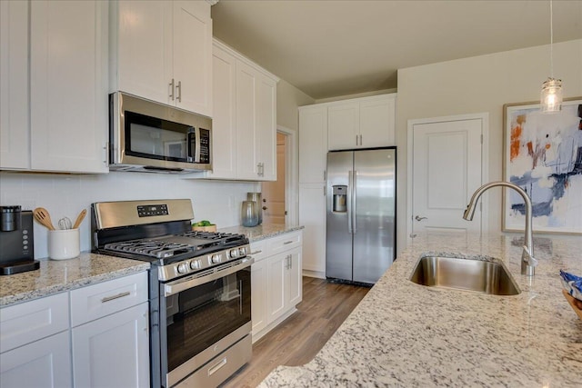 kitchen with sink, white cabinetry, stainless steel appliances, and hanging light fixtures