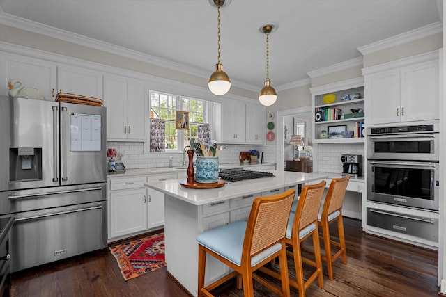 kitchen with ornamental molding, light countertops, white cabinets, appliances with stainless steel finishes, and a warming drawer