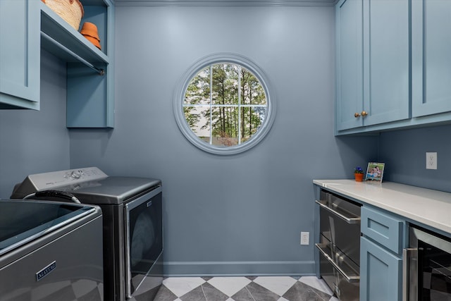 clothes washing area with beverage cooler, baseboards, separate washer and dryer, and cabinet space