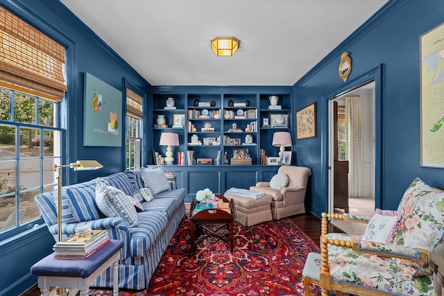 sitting room with ornamental molding, built in features, and wood finished floors