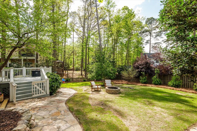 view of yard with fence, a wooden deck, an outdoor fire pit, and a patio area