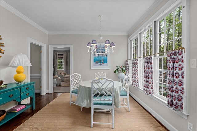 dining room featuring a notable chandelier, plenty of natural light, ornamental molding, and wood finished floors