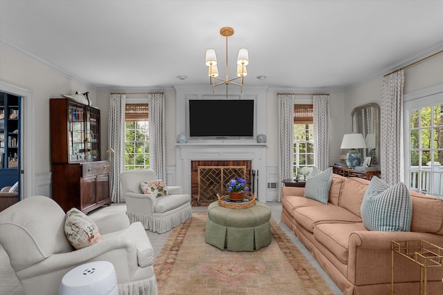 living room with plenty of natural light, a brick fireplace, crown molding, and an inviting chandelier