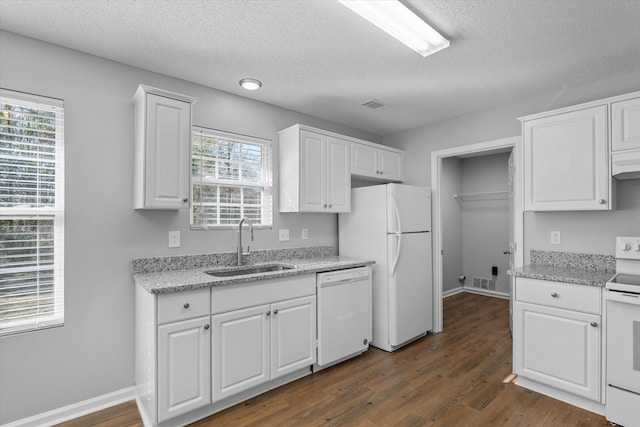 kitchen with white appliances, dark wood-type flooring, light stone countertops, sink, and white cabinetry