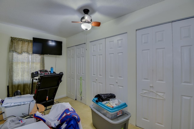 bedroom with light carpet, two closets, a ceiling fan, and a textured ceiling