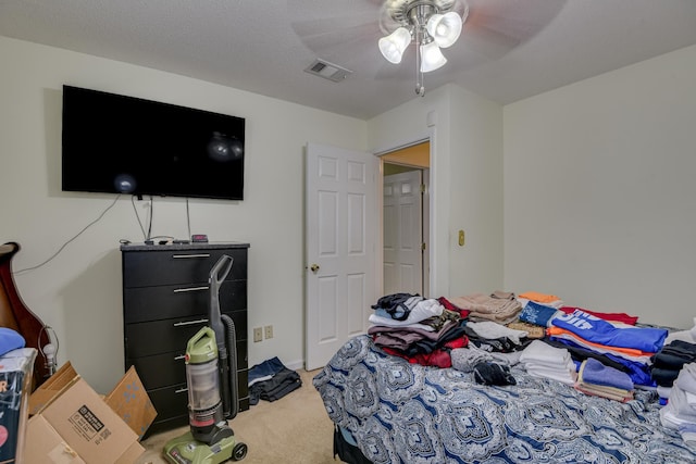 carpeted bedroom featuring visible vents, a textured ceiling, and ceiling fan