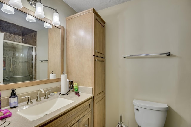 full bath featuring vanity, toilet, a shower stall, and a textured ceiling