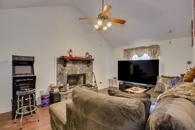 living room with ceiling fan, baseboards, a stone fireplace, and wood finished floors