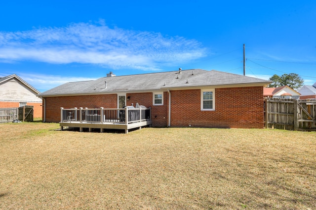 back of house featuring fence, a lawn, brick siding, and a wooden deck