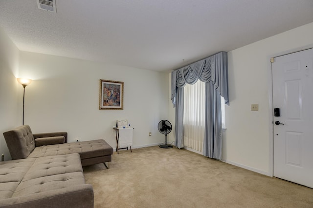 living room featuring light carpet, visible vents, a textured ceiling, and baseboards