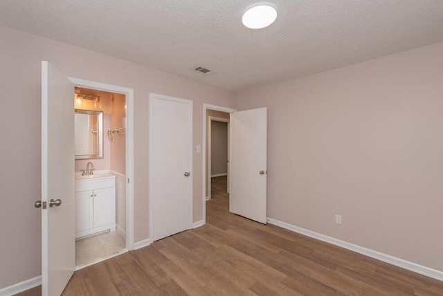 153 Campbell Cir, Hephzibah, GA 30815 - unfurnished bedroom with light wood-style flooring, a textured ceiling, and ensuite bath