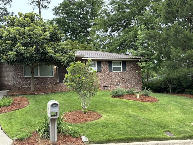 view of front facade featuring brick siding, a front lawn, and metal roof