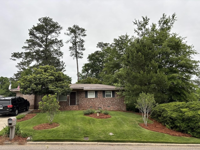 view of front of house featuring a front yard, brick siding, and metal roof