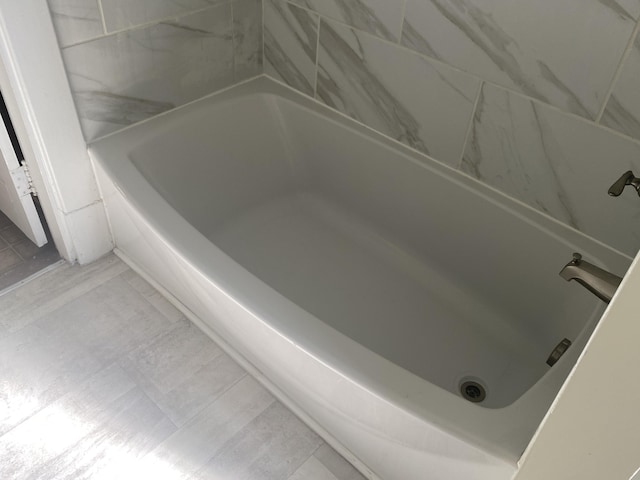 bathroom with tile patterned flooring and a bath