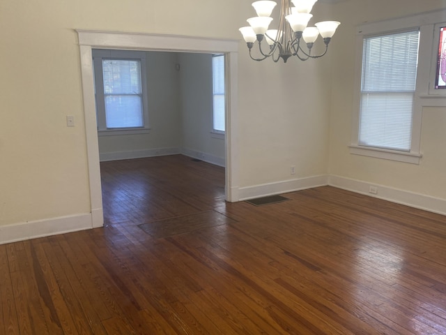 unfurnished dining area with dark hardwood / wood-style flooring and an inviting chandelier