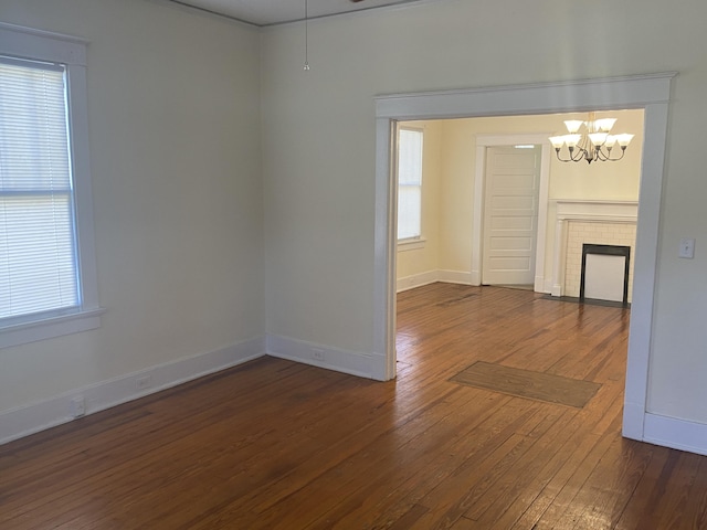 spare room featuring a notable chandelier, dark hardwood / wood-style flooring, and a fireplace