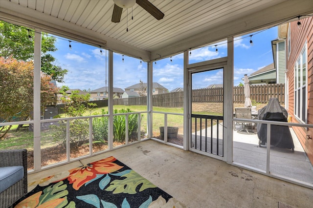 unfurnished sunroom with a ceiling fan, plenty of natural light, and a residential view