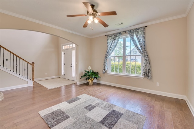 foyer entrance with arched walkways, baseboards, stairs, and wood finished floors