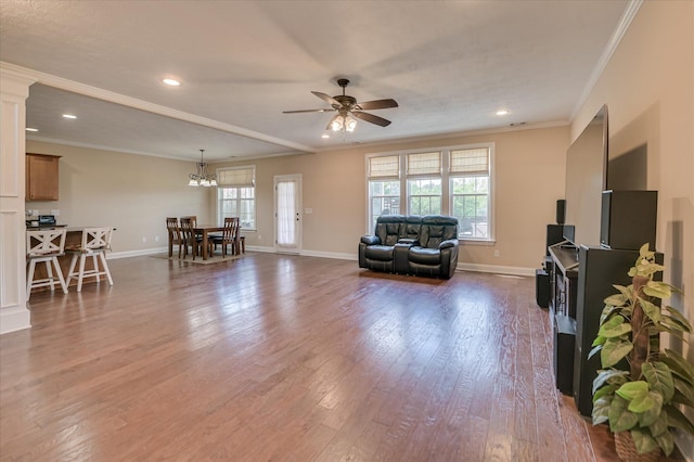 living room featuring crown molding, dark wood-style flooring, baseboards, recessed lighting, and ceiling fan with notable chandelier