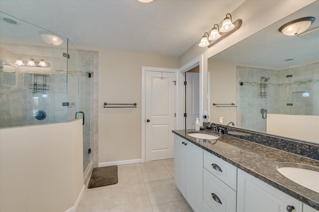 bathroom with baseboards, a shower stall, a sink, and tile patterned flooring