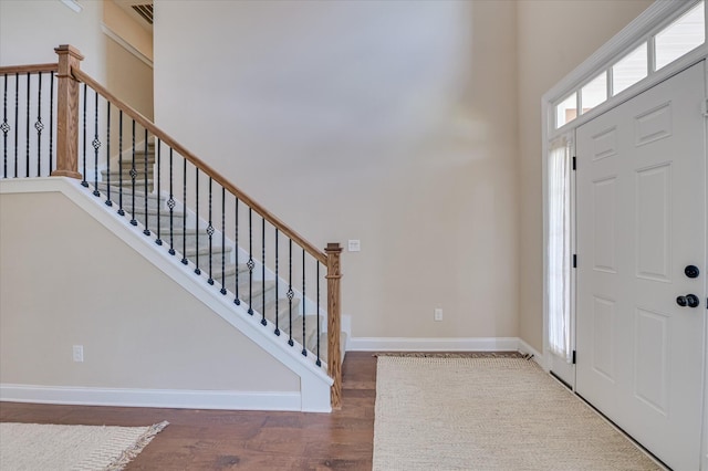 foyer with stairs, baseboards, visible vents, and wood finished floors