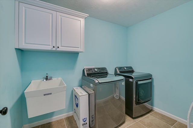 laundry area with cabinet space, a sink, baseboards, light tile patterned floors, and washer and clothes dryer