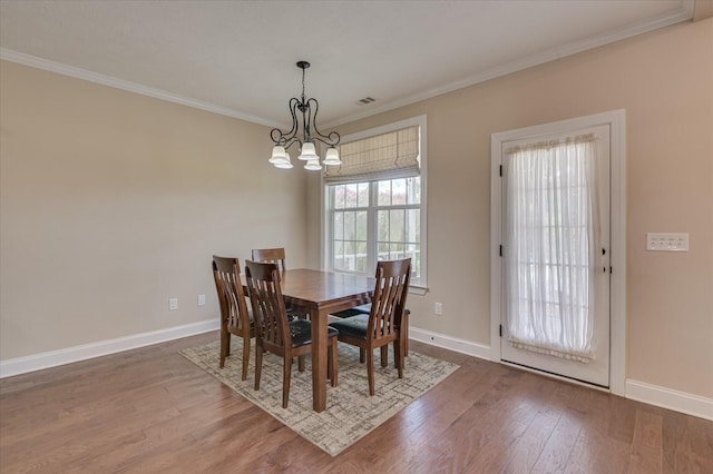 dining space featuring crown molding, baseboards, an inviting chandelier, and wood finished floors