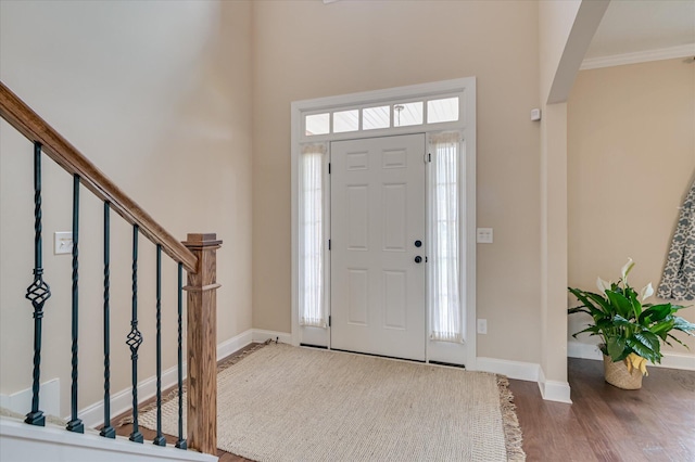 foyer entrance with stairs, wood finished floors, baseboards, a high ceiling, and arched walkways