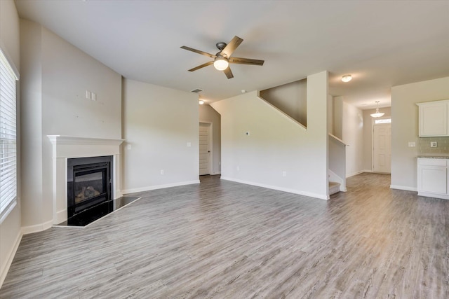 1052 Dietrich Ln, North Augusta, SC 29860 - unfurnished living room with a ceiling fan, stairs, light wood-style flooring, a glass covered fireplace, and plenty of natural light