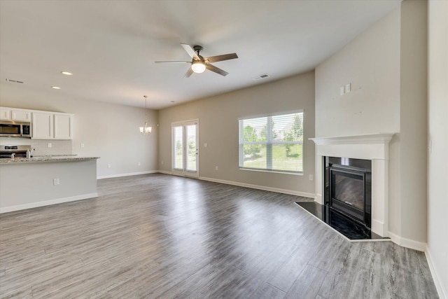 1052 Dietrich Ln, North Augusta, SC 29860 - unfurnished living room with a glass covered fireplace, a ceiling fan, wood finished floors, a chandelier, and recessed lighting