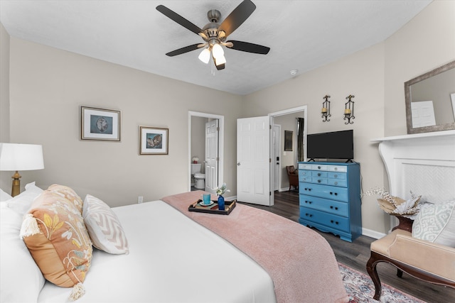 bedroom featuring dark wood-style flooring, baseboards, ceiling fan, and ensuite bath