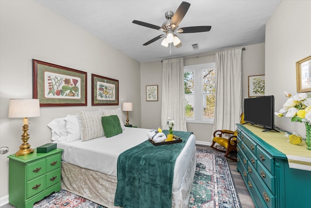 bedroom featuring visible vents, a ceiling fan, baseboards, and wood finished floors