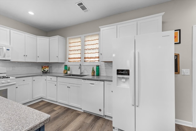 kitchen with visible vents, a sink, white appliances, and tasteful backsplash