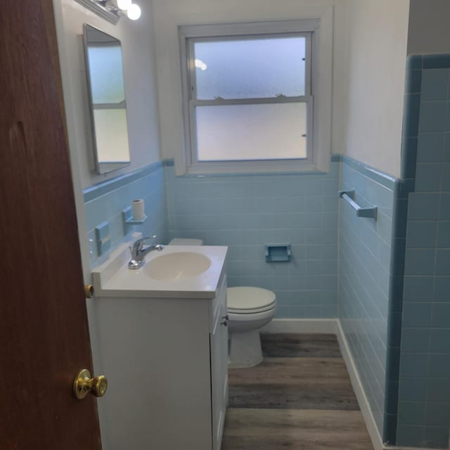 2514 Cascade Dr, Augusta, GA 30904 - bathroom featuring tile walls, wood finished floors, vanity, toilet, and a wainscoted wall