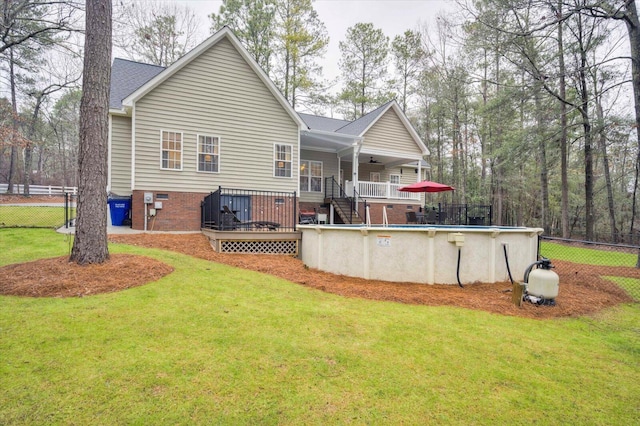 back of property with ceiling fan, a swimming pool side deck, and a lawn