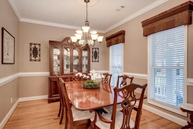 dining space with ornamental molding, a wealth of natural light, an inviting chandelier, and light hardwood / wood-style flooring