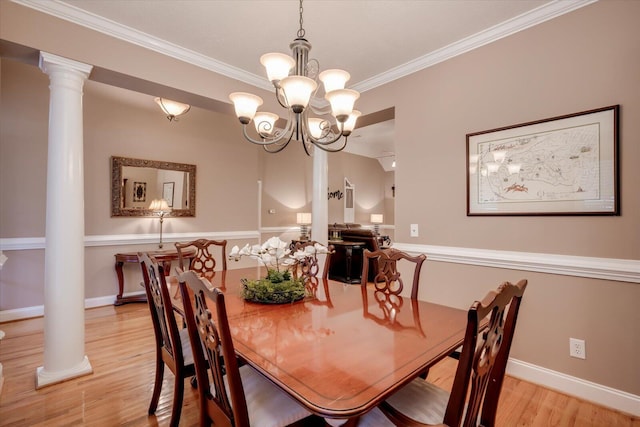 dining area featuring a notable chandelier, light wood-type flooring, ornamental molding, and ornate columns