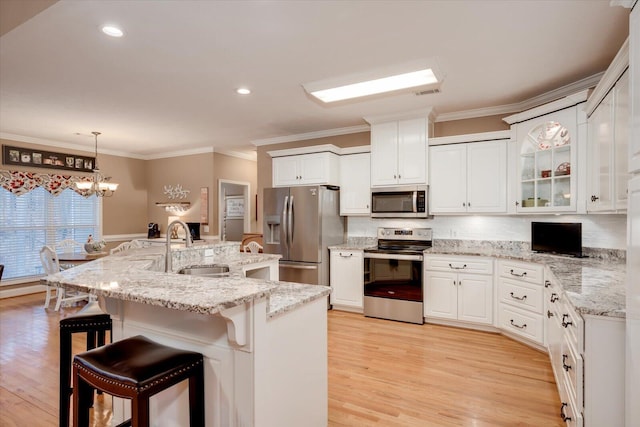 kitchen with appliances with stainless steel finishes, decorative light fixtures, sink, white cabinets, and a kitchen breakfast bar