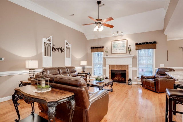 living room featuring vaulted ceiling, ornamental molding, a wealth of natural light, and light hardwood / wood-style floors